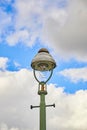 View from below of an old Berlin street lamp in front of a blue and cloudy sky