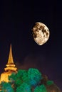 A view of an old Buddhist stupa illuminated in golden light with a huge moon Royalty Free Stock Photo