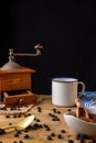 View of old coffee grinder with white cup, coffee beans, brown sugar and spoon on wooden table and black background, Royalty Free Stock Photo