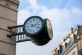 View of an old green analog clock on a street corner in Strasbourg in winter