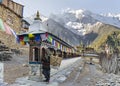 Old local woman spinning prayer wheels with a snow avalanche on Annapurna II mountain in the background  Upper Pisang  Nepal Royalty Free Stock Photo