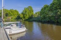 View of old man in parked motor boat. Beautiful green trees on coast on blue sky background. Sweden. Europe.