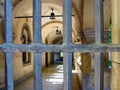 View through an old metal grating of courtyard of an ancient building with arched vaults and exquisite lamps. European