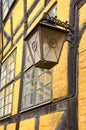 An old metallic lantern hanging from a yellow brick wall in Copenhagen, Denmark