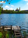 View on old orthodox church on shore of the beautiful lake and small wooden pier with bench for fishing Royalty Free Stock Photo