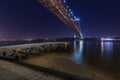 View of an old pier in the banks of the Tagus River Rio Tejo with the 25 of April Bridge on the backgound at night Royalty Free Stock Photo