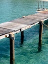 View of old rustic wooden plank bridge, pathway of pier or local port to the speed boat, over the blue sea background in island,. Royalty Free Stock Photo