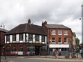 a view of old square in aston under lyne with pub shops and passer by