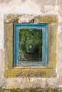 View of old window with frames in blue wood, glass with reflection of a staircase in the forest with tunnel effect Royalty Free Stock Photo