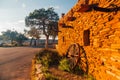 View of an old wooden wagon wheel leaning on an old stone wall during sunset Royalty Free Stock Photo