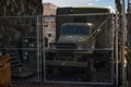View of old WWII military truck parked in an alley behind a metal fence. gmc cckw