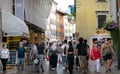 View of one of the main pedestrian streets in the historic center of Trento. Historic buildings and people strolling wearing masks