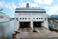 View of the open cargo deck hatches of a sea ferry moored to the pier against the background of the bay.