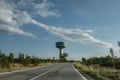 View of an open road in the countryside with a bright blue sky with a water tower in the distance