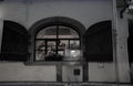 View through open shuttered window to man in restaurant inside and ghostly blurred figure of passing person