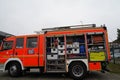 View on orange fire-brigade truck with open side door of stowage place.