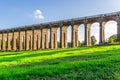 A view of the Ouse Valley Viaduct Balcombe Viaduct in the summer with bright sun shining through the arches onto the grass