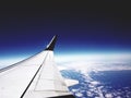 Airplane wing over cloudy earth surface with dark blue horizon