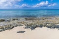A view out to sea across a rocky shoreline on a quiet beach on the island of Eleuthera, Bahamas