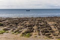 A view out to sea towards tourist boats offshore across the sea eroded boulders on the beach at Old Hunstanton, Norfolk, UK Royalty Free Stock Photo