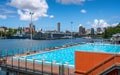 View of outdoor Andrew Boy Charlton Pool with people and Woolloomooloo Finger Wharf and bay in background in Sydney NSW Australia