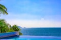 View of the outdoor pool by the sea. There is a lush palm tree next to the pool. Sanya, China.