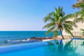 View of the outdoor pool by the sea. There is a lush palm tree next to the pool. Sanya, China. Royalty Free Stock Photo