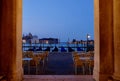 View of the outdoor restaurant with gondolas in the background. Venice, Italy. Royalty Free Stock Photo