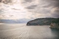 The view over the Adriatic sea coast, the sun rays coming through the cloudy sky and a ship sailing towards the horizin leaving w Royalty Free Stock Photo