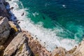 View over the cliffs at the deep ocean and waves swirling at small beach and rocks at Cape Point South Africa Royalty Free Stock Photo