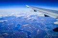 View over the clouds from the porthole of an airplane with plane wing and blue sky over the Como Lake Royalty Free Stock Photo