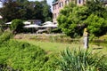 View over creek and green park on outdoor terrace of restaurant with umbrellas and old bred