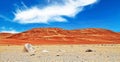 View over dry barren sand pebble desert to beautiful red orange colored sandstone hills in contrast with blue summer sky - Salar Royalty Free Stock Photo