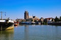 View over dutch inland harbor on skyline of old town with church tower against blue summer sky