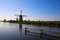 View over dutch water canal on horizon with windmills in rural landscape in morning sun light and dizzy blue sky - Kinderdijk, Royalty Free Stock Photo