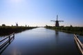 View over dutch water canal on horizon with windmills in rural landscape in morning sun light and dizzy blue sky - Kinderdijk, Royalty Free Stock Photo