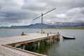 View over the fjord with a wooden jetty, fishing boat, and beautiful mountains & islands in the background, Eskifjordur, Iceland. Royalty Free Stock Photo