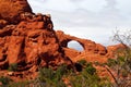 View over green plants on red sandstone rock wall with natural stone arch - Devils garden, Arches national park, Utah Royalty Free Stock Photo