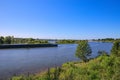 View over green rural landscape on river Maas with inland waterway vessel against blue summer sky - Between Roermond and Venlo,