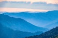 View over the Green Valley, surrounded by high mountains on a pink summer sunset. Layers of mountains in the haze during sunset