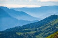 View over the Green Valley, surrounded by high mountains on a summer sunset. Layers of mountains in the haze during sunset