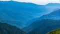 View over the Green Valley, surrounded by high mountains on a summer sunset. Layers of mountains in the haze during sunset