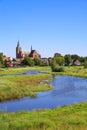 View over green wetland water on cityscape of durch town with tower of medieval church against blue summer sky - Neer Limburg, Royalty Free Stock Photo