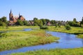 View over green wetland water on cityscape of durch town with tower of medieval church against blue summer sky - Neer Limburg, Royalty Free Stock Photo