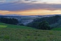 View over Hills covered by endless Forest at Sunset, fog in the valleys, grass meadow in front Royalty Free Stock Photo