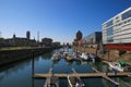 View over marina on modern silver office buildings five boats against blue sky