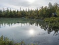 View over milky green Laitaure lake, hills, birch and spruce tree forest with small shelter and rowing boats. Lapland landscape at