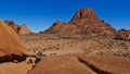 View over mountain Spitzkoppe, Kalahari, Namibia, with water pond and round shaped brownish rocks at sunny day with blue sky. Royalty Free Stock Photo