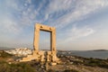 View over Naxos old town throught the ruins of ancient marble doorway monument Portara at sunset, Greece.