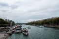 View over the river Seine with boats and people walking on the sidewalk under a cloudy sky Royalty Free Stock Photo